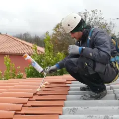 Trabajador aplicando espuma para impermeabilizar tejado de tejas.