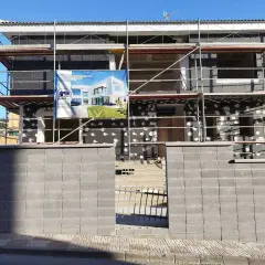 Edificio en construcción con andamios. Un cartel muestra un diseño moderno, quizás para una **ley propiedad horizontal sate**.