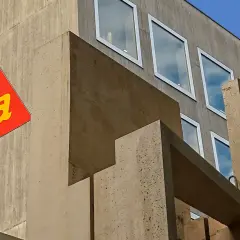 Edificio moderno de hormigón con el logo de Sika en rojo y amarillo.