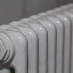 Radiador de mica blanco, con sus aletas curvas y un detalle de conexión en un extremo.