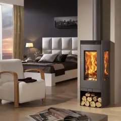 Estufa moderna de leña, un ejemplo de los diversos tipos de estufas, calienta un dormitorio acogedor con vistas al atardecer.
