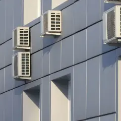 Múltiples unidades de aire acondicionado en fachada exterior de edificio moderno.