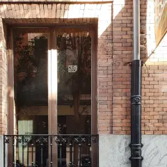 Fachada de ladrillo con ventanas y puerta de madera. El mantenimiento de fachadas es clave para conservar su belleza y estructura.