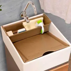 Lavaderos pequeños bien organizados con compartimentos para jabón y cepillo. Al lado, una lavadora y una planta.