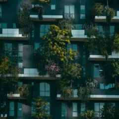 Edificio moderno con balcones repletos de vegetación, un ejemplo de sostenibilidad en la construcción que integra la naturaleza en la vida urbana.
