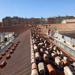 Trabajadores en un tejado, reemplazando tejas como parte de la rehabilitación de edificios antiguos.