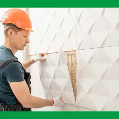 Obrero coloca paneles 3D blancos, una solución moderna para forrar una pared con humedad.