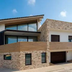Casa moderna con revestimiento de piedra y madera, ideal para quienes buscan cómo revestir una pared exterior con estilo y durabilidad.
