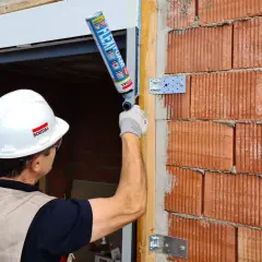 Un trabajador aplica espuma expansiva, que contiene diisocianatos, para sellar un marco de ventana en una pared de ladrillos.