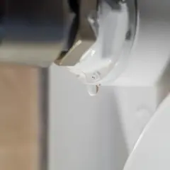 Gota de agua cayendo de un componente metálico, indicando la necesidad de desmontar radiador para reparación.