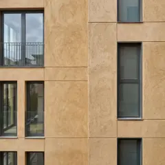 Fachada moderna con acabado de mortero para reparación, ventanas rectangulares y balcones con barandillas metálicas.
