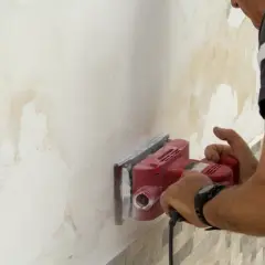 Hombre lijando pared con manchas de humedad para arreglar humedades.