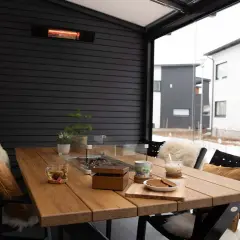 Mesa de madera en terraza cerrada con calefactor, ideal para disfrutar de una bebida caliente en invierno.