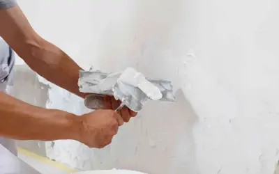 Man applying enfoscado de mortero a una pared con una llana.