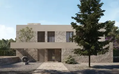 Una casa moderna con fachada de piedra y estuco, ideal para renovar fachada casa. El camino de entrada conduce a una puerta de madera.