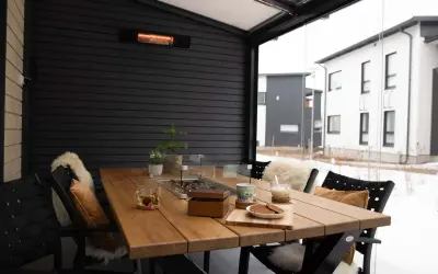 Mesa de madera en terraza cerrada con calefactor, ideal para disfrutar de una bebida caliente en invierno.