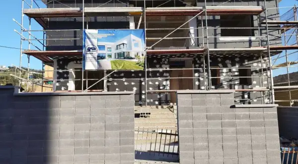 Edificio en construcción con andamios. Un cartel muestra un diseño moderno, quizás para una **ley propiedad horizontal sate**.