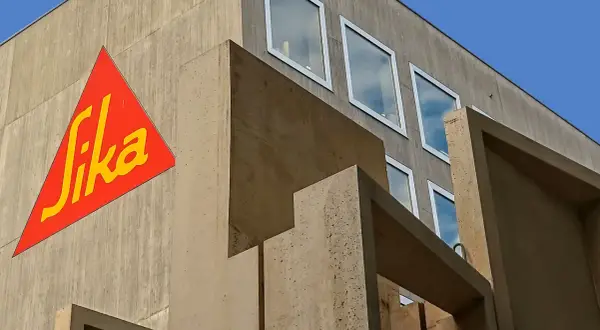 Edificio moderno de hormigón con el logo de Sika en rojo y amarillo.