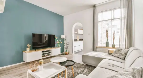 Ideas pintar salón en dos colores: pared azul verdoso y blanca, con sofá gris y muebles modernos.