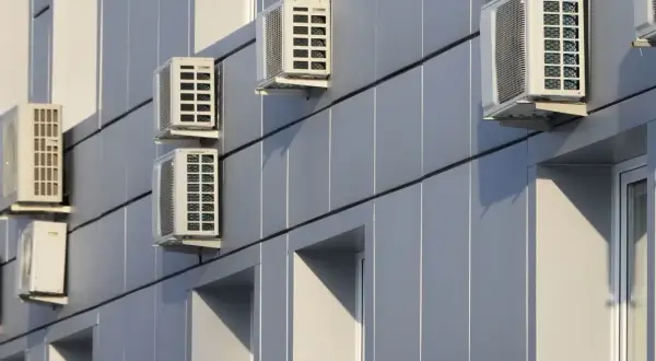 Múltiples unidades de aire acondicionado en fachada exterior de edificio moderno.