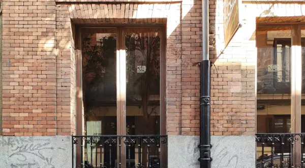 Fachada de ladrillo con ventanas y puerta de madera. El mantenimiento de fachadas es clave para conservar su belleza y estructura.