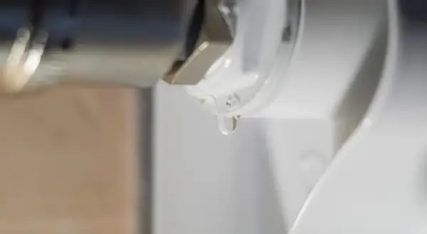 Gota de agua cayendo de un componente metálico, indicando la necesidad de desmontar radiador para reparación.