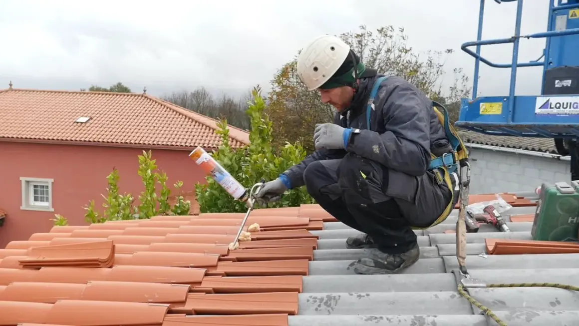Trabajador aplicando espuma para impermeabilizar tejado de tejas.