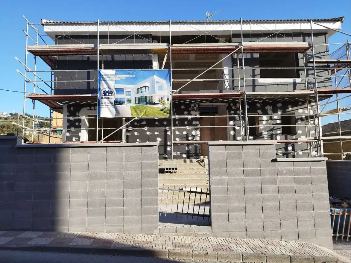 Edificio en construcción con andamios. Un cartel muestra un diseño moderno, quizás para una **ley propiedad horizontal sate**.