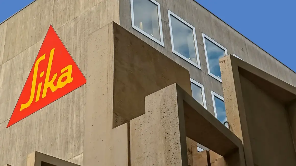 Edificio moderno de hormigón con el logo de Sika en rojo y amarillo.