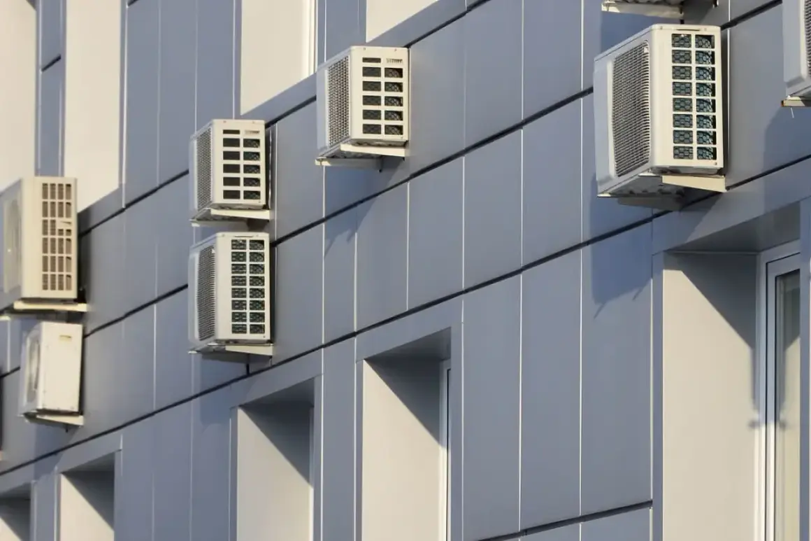 Múltiples unidades de aire acondicionado en fachada exterior de edificio moderno.