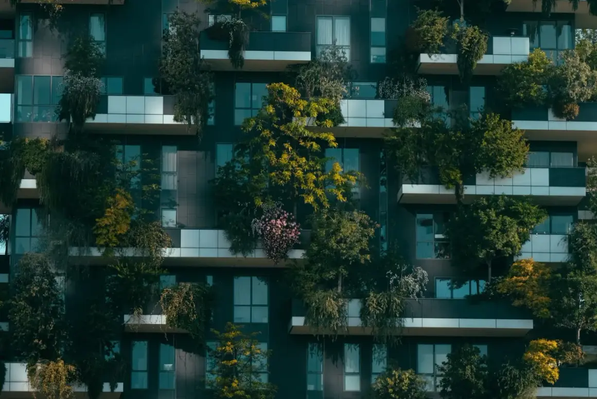Edificio moderno con balcones repletos de vegetación, un ejemplo de sostenibilidad en la construcción que integra la naturaleza en la vida urbana.