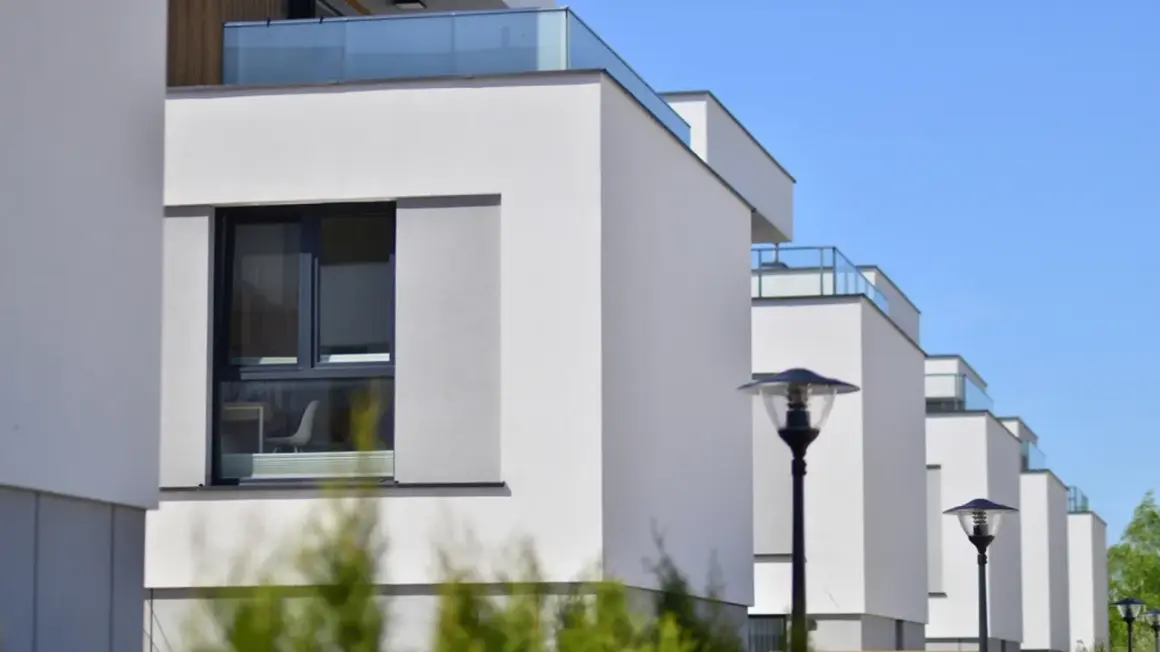 Edificios modernos con fachadas blancas y balcones de cristal, cumpliendo la normativa sobre estética fachadas de edificios.