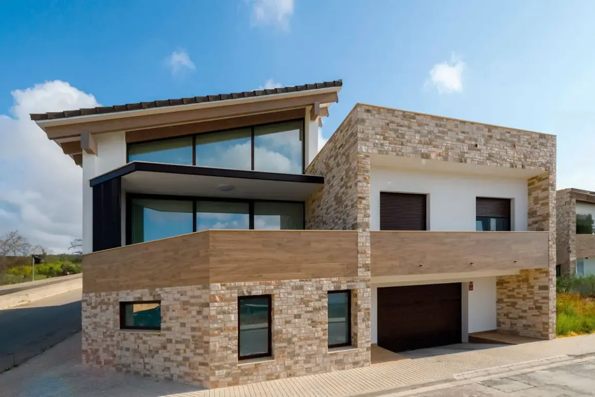 Casa moderna con revestimiento de piedra y madera, ideal para quienes buscan cómo revestir una pared exterior con estilo y durabilidad.