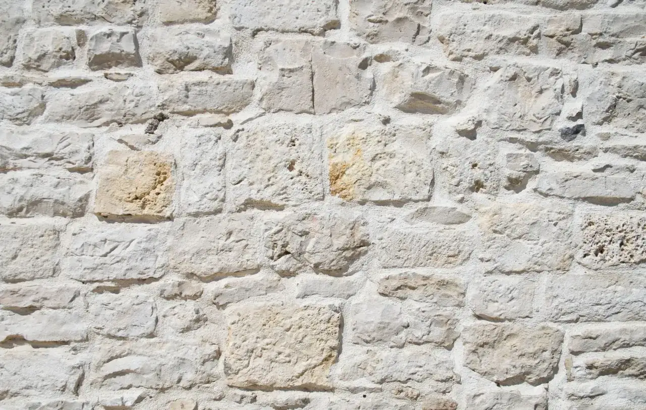 Muro de piedra rústica con una mezcla de cal y arena para revestir paredes, mostrando la textura irregular de las rocas.