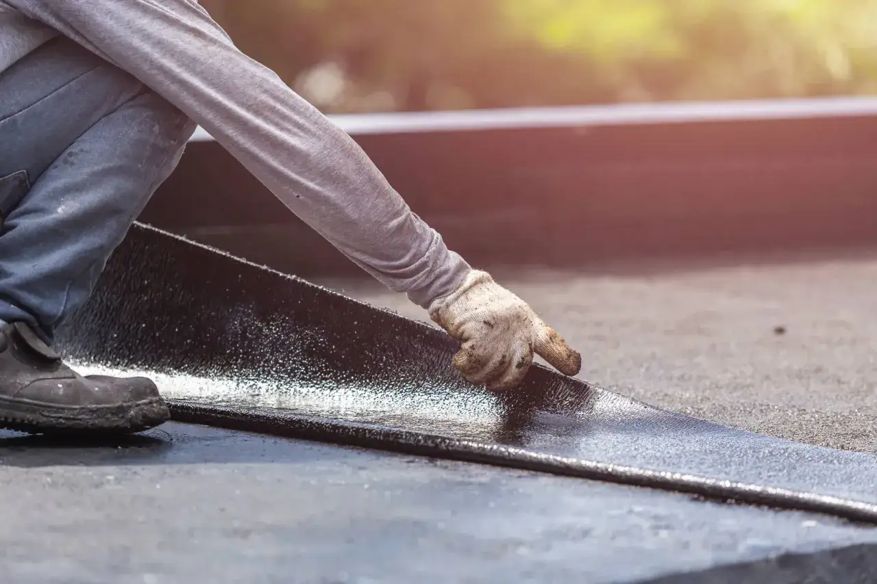 Un trabajador instala una membrana bituminosa, parte esencial de sistemas de impermeabilización para proteger edificaciones.
