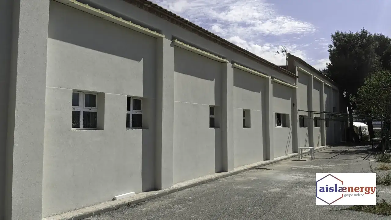 Edificio industrial con fachada de estuco gris y ventanas cuadradas. El logo de