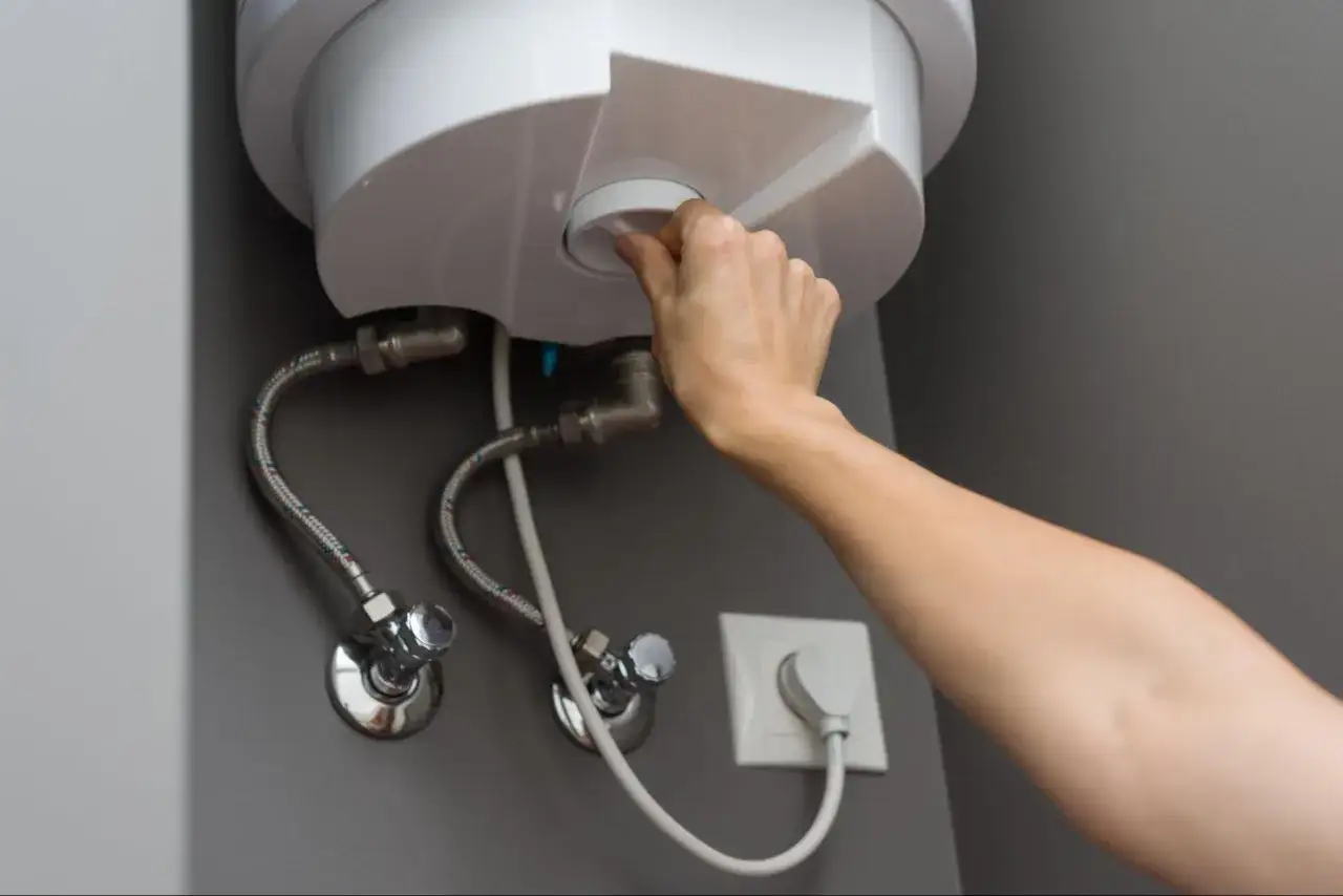 Mano girando la perilla para vaciar un termo eléctrico.