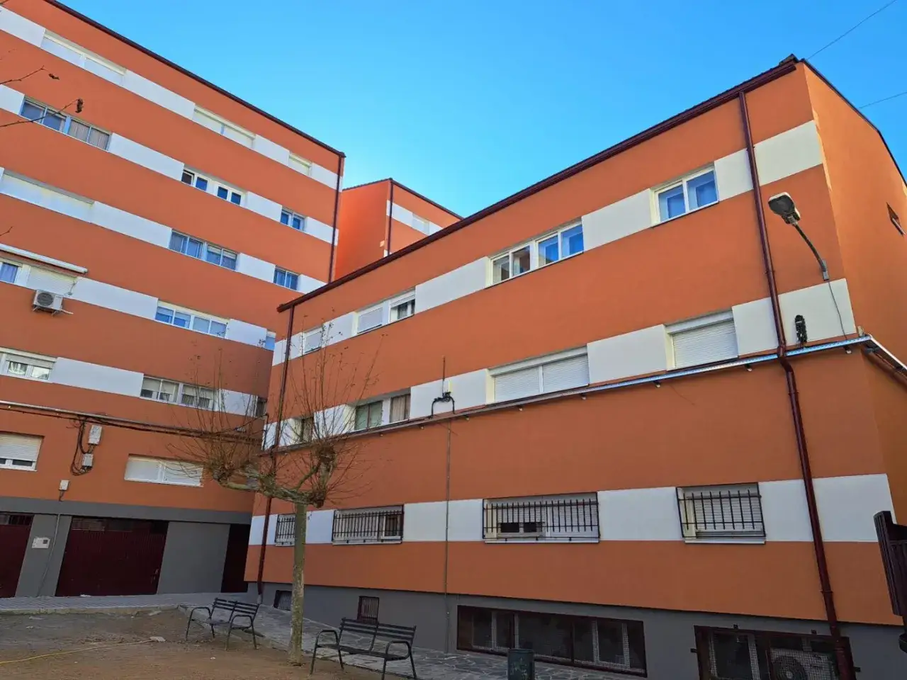 Edificios residenciales con fachada naranja y franjas blancas, resultado de una rehabilitación de edificios que les ha dado un nuevo aire.