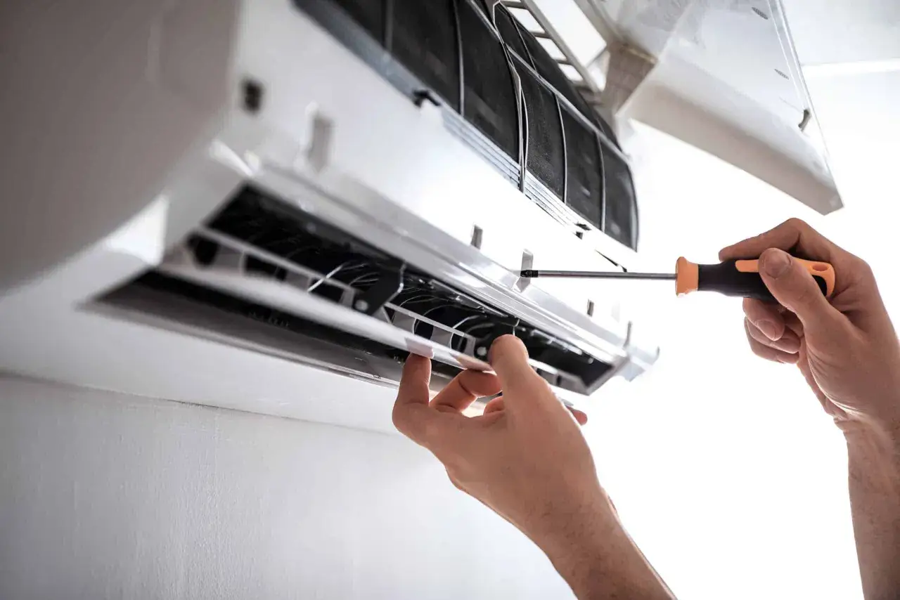 T&eacute;cnico ajustando un aire acondicionado inverter con un destornillador.