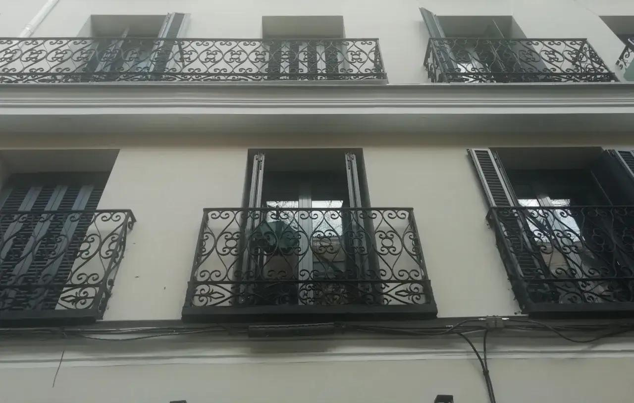 Fachada de edificio con balcones de hierro forjado, parte de un proyecto de rehabilitaci&oacute;n de edificios antiguos.