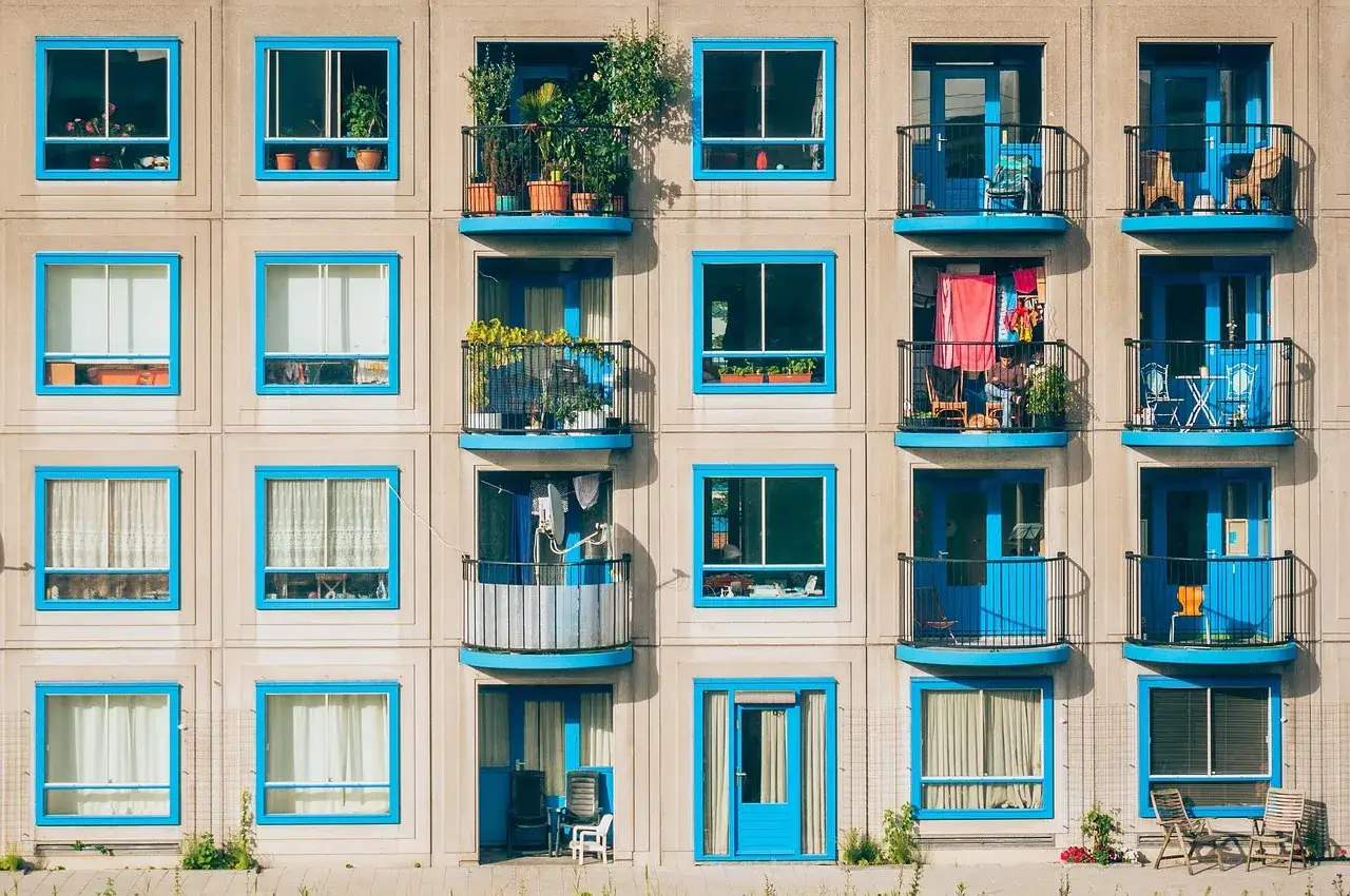 Fachada de edificio con ventanas y balcones de marcos azules, mostrando la diversidad de la vida en cada unidad, un ejemplo de normativa sobre estética fachadas de edificios.