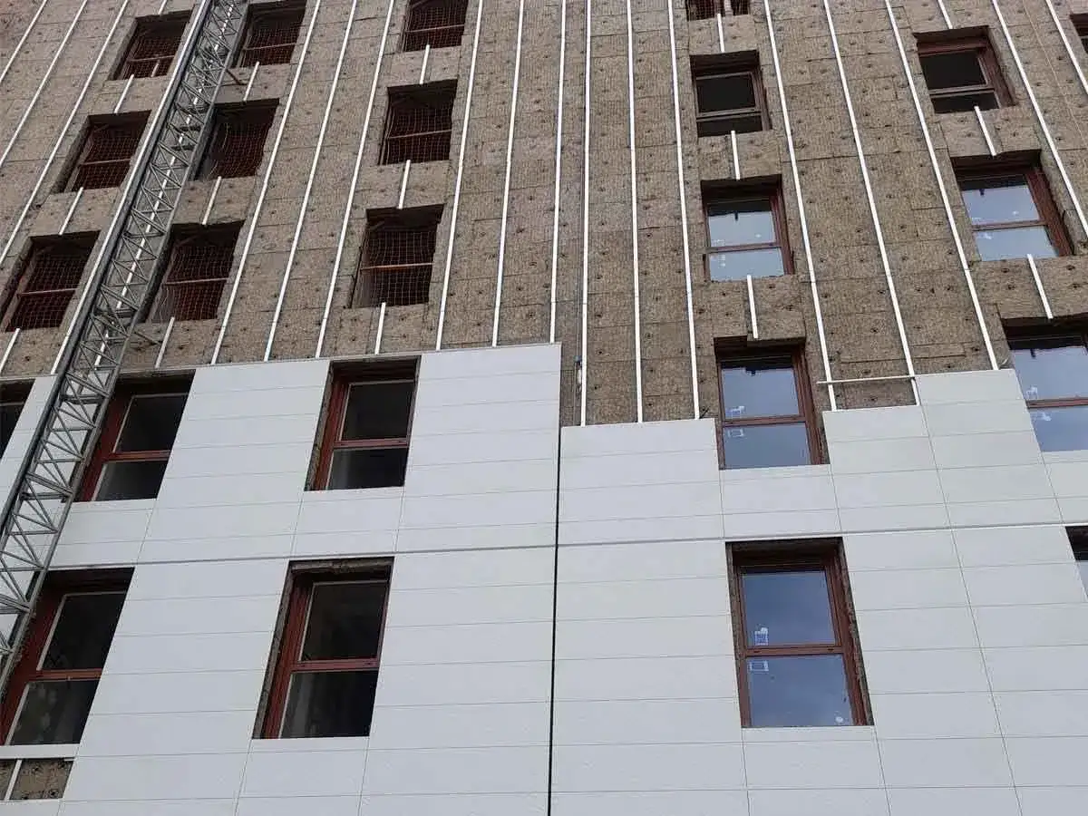 Fachadas rehabilitadas en proceso de construcci&oacute;n, con aislamiento visible y ventanas de madera.