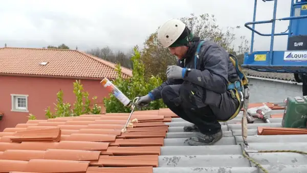 Trabajador aplicando espuma para impermeabilizar tejado de tejas.