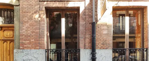 Fachada de ladrillo con ventanas y puerta de madera. El mantenimiento de fachadas es clave para conservar su belleza y estructura.