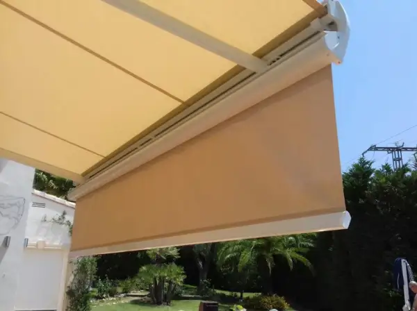Toldo desplegado, listo para cambiar tela. Sombra agradable en el jardín con palmeras.