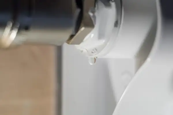 Gota de agua cayendo de un componente metálico, indicando la necesidad de desmontar radiador para reparación.